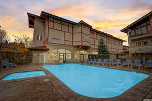 Pool at dusk featuring a patio