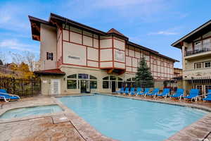 View of pool with a patio area and a hot tub