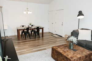 Dining area featuring vaulted ceiling, a chandelier, and LVP flooring