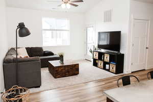 Living room featuring LVP flooring, vaulted ceiling, and ceiling fan