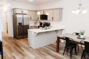 Kitchen featuring kitchen peninsula, pendant lighting, appliances with stainless steel finishes, light LVP flooring, and gray cabinets