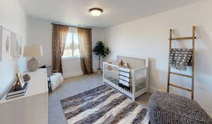 Bedroom featuring light carpet and a crib