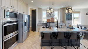 Kitchen featuring pendant lighting, white cabinetry, a large island, light stone counters, and stainless steel appliances