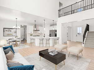 Living room featuring a high ceiling, a chandelier, and light hardwood / wood-style floors