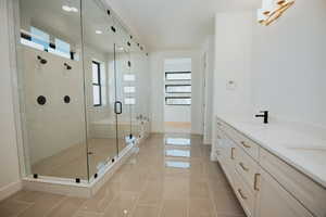 Bathroom featuring tile patterned floors, vanity, a shower with shower door, and a wealth of natural light