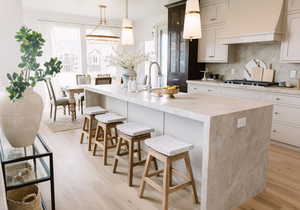 Kitchen with premium range hood, a kitchen island with sink, and a breakfast bar