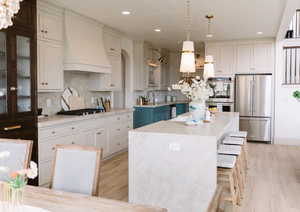 Kitchen with sink, a center island, hanging light fixtures, custom range hood, and stainless steel appliances