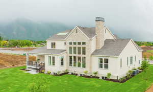 Rear view of property featuring cooling unit, a mountain view, and a lawn