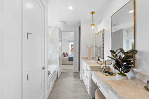 Bathroom with concrete flooring, vanity, and a washtub