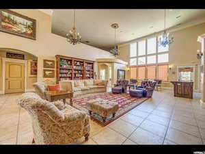 Tiled living room featuring a towering ceiling and a chandelier