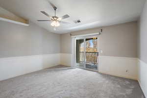 Empty room with vaulted ceiling, ceiling fan, and carpet flooring