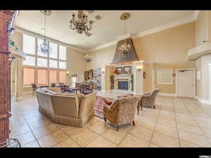 Tiled living room with ornamental molding, a towering ceiling, and an inviting chandelier