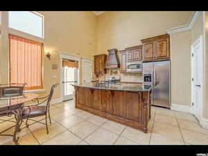 Kitchen featuring premium range hood, appliances with stainless steel finishes, tasteful backsplash, and light tile patterned flooring