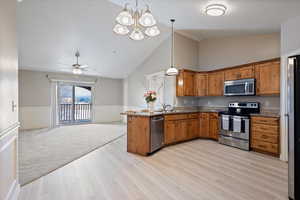 Kitchen featuring decorative light fixtures, kitchen peninsula, sink, light hardwood / wood-style flooring, and stainless steel appliances