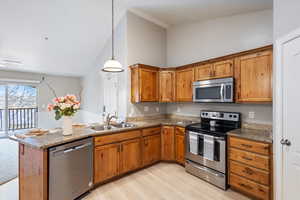 Kitchen with stainless steel appliances, kitchen peninsula, hanging light fixtures, and sink