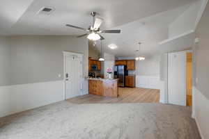 Kitchen featuring lofted ceiling, decorative light fixtures, stainless steel appliances, ceiling fan, and light colored carpet