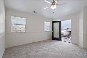 Empty room with light carpet, ceiling fan, and a wealth of natural light