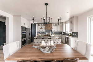 Dining area with light hardwood / wood-style floors, sink, and an inviting chandelier