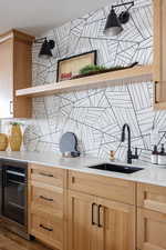 Kitchen featuring decorative backsplash, sink, light brown cabinets, and wine cooler