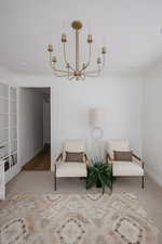 Living area featuring light colored carpet, a notable chandelier, and ornamental molding