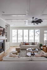 Living room featuring built in features, a high end fireplace, ceiling fan, and light hardwood / wood-style flooring