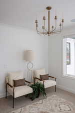 Living area featuring ornamental molding, a chandelier, and carpet flooring