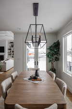 Dining area with wood-type flooring, a chandelier, french doors, ornamental molding, and built in features