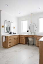 Bathroom featuring a wealth of natural light, vanity, and ornamental molding