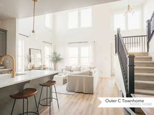 Living room featuring sink, light hardwood / wood-style floors, a chandelier, and a high ceiling