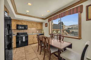 Kitchen with a mountain view, backsplash, black appliances, and ornamental molding