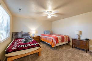 Bedroom with ceiling fan, carpet, and a textured ceiling