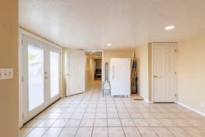 Tiled spare room with a textured ceiling and french doors