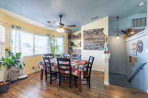 Dining space with ceiling fan, lofted ceiling, and dark hardwood / wood-style flooring