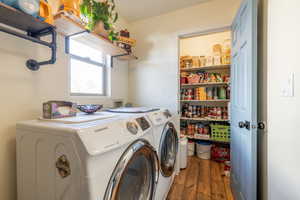 Clothes washing area with washing machine and dryer and dark hardwood / wood-style flooring