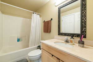 Full bathroom featuring toilet, a textured ceiling, shower / tub combo, and vanity