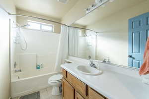 Full bathroom with vanity, toilet, tile patterned floors, and shower / tub combo with curtain