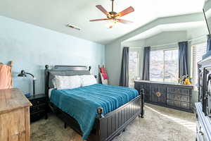 Carpeted bedroom with ceiling fan and vaulted ceiling