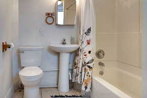 Full bathroom with toilet, sink, tile patterned flooring, and shower / bath combo