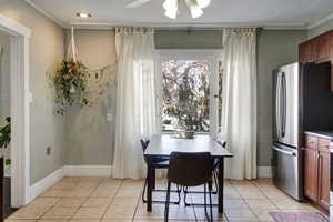 Dining space featuring ceiling fan, ornamental molding, and light tile patterned flooring