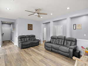 Living room with light hardwood / wood-style floors and ceiling fan