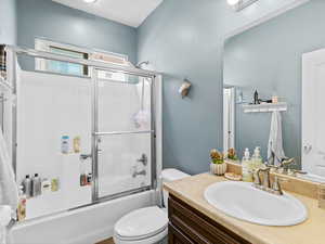 Full bathroom with toilet, enclosed tub / shower combo, and vanity