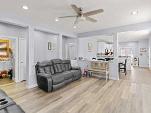 Living room featuring light wood-type flooring, ceiling fan, and washer and clothes dryer