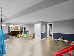 Game room featuring light wood-type flooring and a textured ceiling