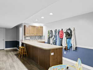 Kitchen featuring light wood-type flooring, kitchen peninsula, tasteful backsplash, and a breakfast bar