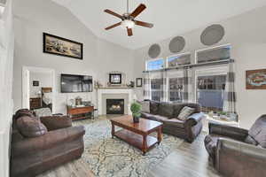 Living room with hardwood / wood-style flooring, ceiling fan, a fireplace, and lofted ceiling