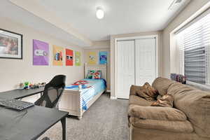 Carpeted bedroom with a closet and a textured ceiling