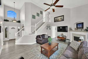 Living room with ceiling fan, a high ceiling, and wood-type flooring