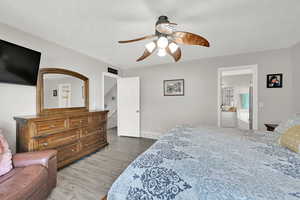 Bedroom with ceiling fan, hardwood / wood-style flooring, and ensuite bath