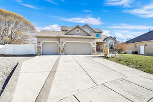 View of front of home with a garage, a front yard, and central AC