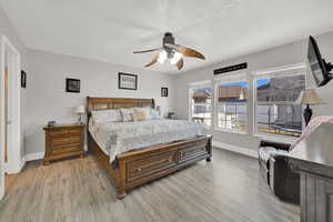 Bedroom with ceiling fan, a textured ceiling, and light hardwood / wood-style flooring